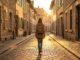 Femme voyageant seule dans une ruelle pittoresque européenne au coucher du soleil, sentiment de liberté