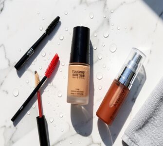 Produits de maquillage waterproof disposes sur une surface en marbre sous une lumiere estivale avec des gouttes d eau