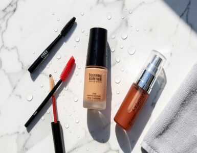 Produits de maquillage waterproof disposes sur une surface en marbre sous une lumiere estivale avec des gouttes d eau