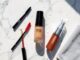 Produits de maquillage waterproof disposes sur une surface en marbre sous une lumiere estivale avec des gouttes d eau