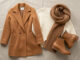 Pièces mode automne-hiver posées à plat : manteau camel, grosse maille et écharpe oversize