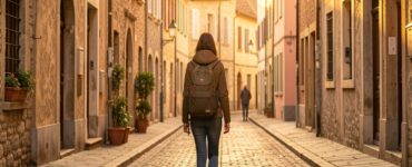 Femme voyageant seule dans une rue pavée européenne au coucher du soleil, symbole de liberté et de voyage solo