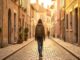 Femme voyageant seule dans une rue pavée européenne au coucher du soleil, symbole de liberté et de voyage solo